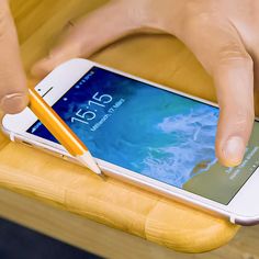 a person holding a cell phone with a pencil in their hand and writing on the screen