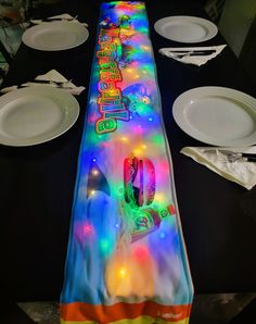 the table is set with white plates and black cloths, which have colorful lights on it