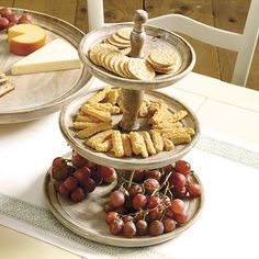 three tiered trays filled with crackers and grapes on top of a table