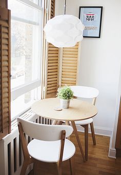 a table with two chairs and a vase on it in front of a large window