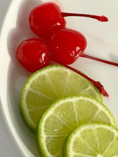 limes and cherries are arranged in a bowl