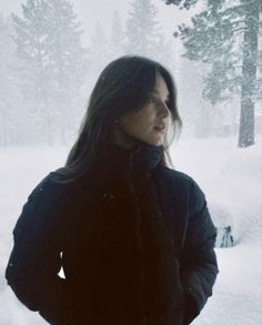 a woman standing in the snow with her hands on her hips and looking off into the distance