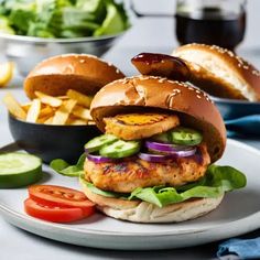 a chicken burger with lettuce, tomato and cucumber on a plate