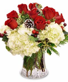 a vase filled with red roses and white hydrangeas on top of a table