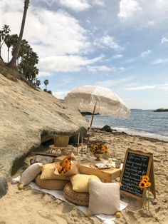 an umbrella is set up on the beach with sunflowers and other items for seating