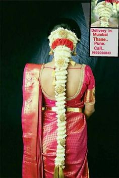 the back of a woman's head wearing a pink and gold saree with flowers in her hair