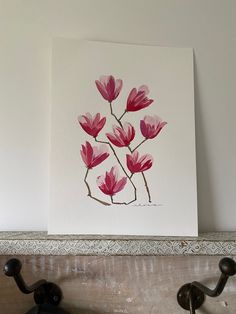 a painting of pink flowers on a white wall next to two coat hooks and a hook