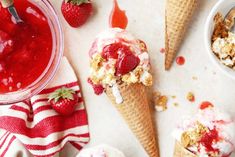 three scoops of ice cream with strawberries and other toppings on the table