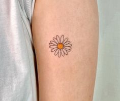 a woman's arm with a small daisy tattoo on it