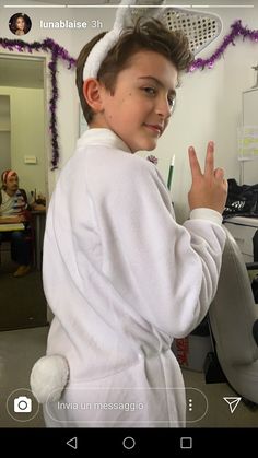 a young boy in a bathrobe making the peace sign