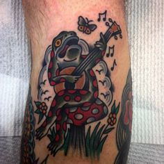 a tattoo on the leg of a man with music notes and a frog holding a guitar