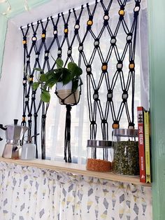 a shelf with plants and spices on it in front of a window covered by curtains