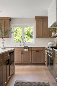 a kitchen with wooden cabinets and stainless steel appliances, along with white counter tops that match the wood flooring