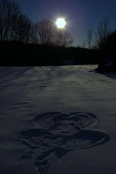 a snow covered field with the moon in the background