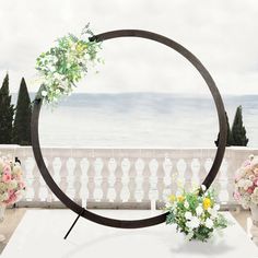 an outdoor ceremony setup with flowers and greenery in front of the ocean on a cloudy day