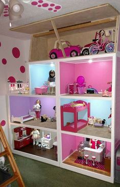 a pink and white doll house with lots of toys on top of it's shelves