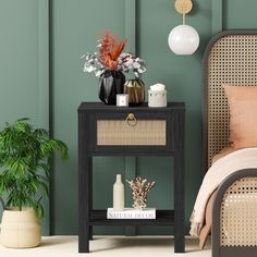 a bedroom with green walls and a black end table next to a bed, potted plants on the nightstand