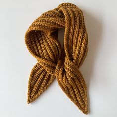 a brown knitted scarf laying on top of a white table