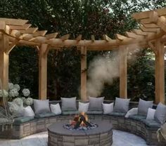 an outdoor fire pit surrounded by wooden pergols and seating area with white pillows