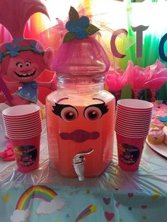 a table topped with lots of pink cups and plastic cupcakes next to each other