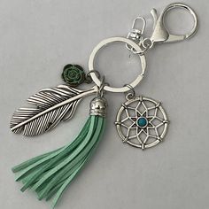 a keychain with a dream catcher charm and a green tassel on it