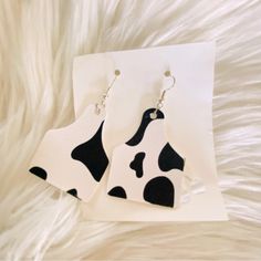 pair of cow print earrings on white fur