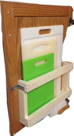 a wooden cabinet with two cutting boards attached to the door and one green file folder