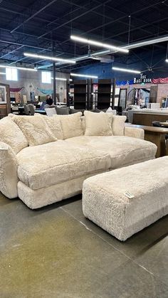 an overstuffed couch and ottoman are on display in a furniture store with other items