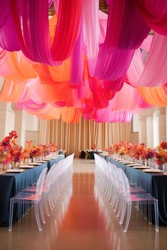 the tables are lined with clear acrylic chairs and colorful drapes hanging from the ceiling