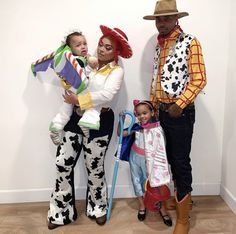 three adults and two children dressed up as toy story characters, standing in front of a white wall