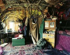 a bed room with lots of clothes hanging from the ceiling and rugs on the floor