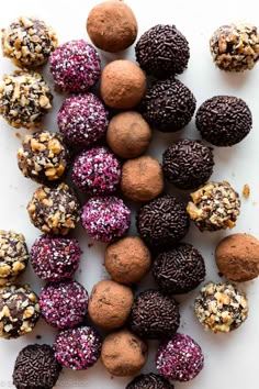 chocolate truffles with sprinkles and nuts arranged on a white surface