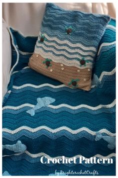 a blue crocheted blanket sitting on top of a couch next to a pillow