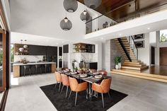 a dining room and kitchen area in a modern home with stairs leading up to the second floor