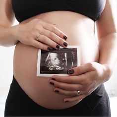 a pregnant woman holding an old photo in her belly