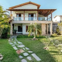 a house that is in the grass with some trees and bushes around it's perimeter