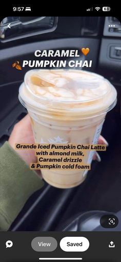 someone is holding up a cup of pumpkin chai in their hand while driving the car