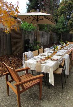 an outdoor dining table set up with white linens and place settings for eight people