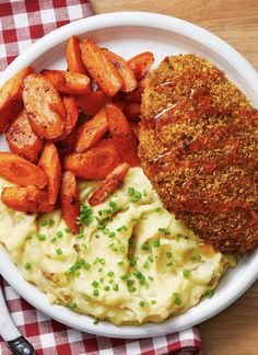 a white plate topped with mashed potatoes and meat patties next to carrots