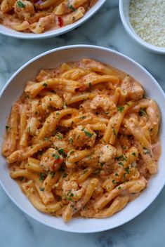 two white bowls filled with pasta and sauce