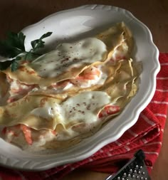 a white plate topped with ravioli next to a grater on a red and white towel