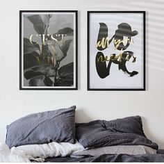 two black and white pictures hanging on the wall above a bed in a room with grey linens