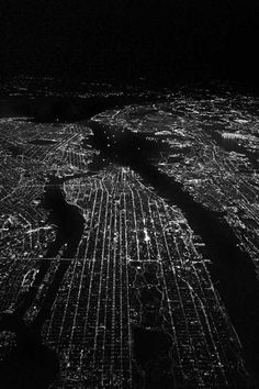 black and white photograph of an aerial view of the city lights at night from above