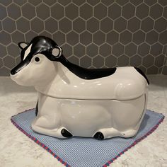 a ceramic cow sitting on top of a blue and white place mat next to a tile wall