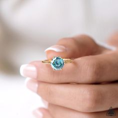 a woman's hand holding a blue diamond ring