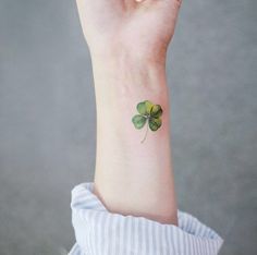 a small four leaf clover tattoo on the wrist