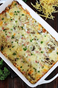 a casserole dish with broccoli, cheese and meat in it on a wooden table