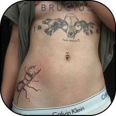 a woman's stomach with tattoos on it and the words brugus written in black ink