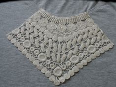 a white crocheted doily on top of a gray shirt