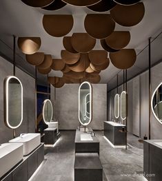 a bathroom with several sinks and mirrors on the walls, along with lights hanging from the ceiling